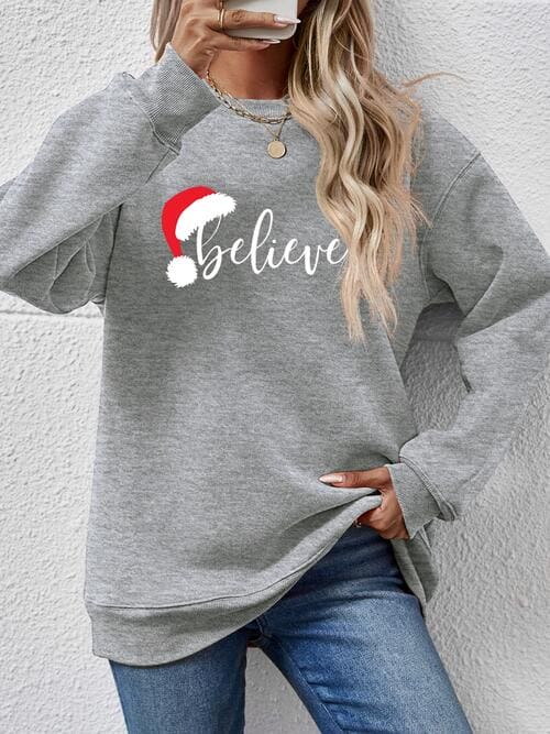 a woman wearing a grey sweatshirt with the word believe on it